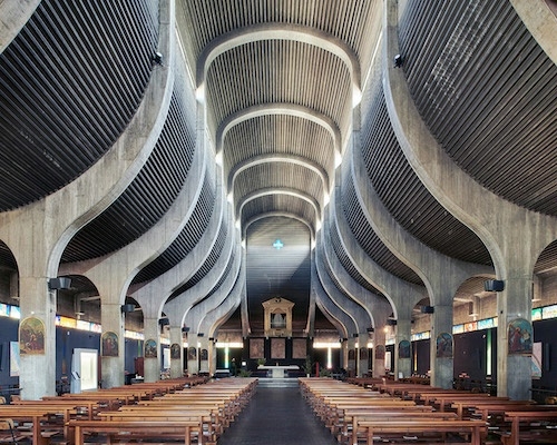 photo of the spacious interior with lofty dramatic ribbed ceiling and rows of wooden pews