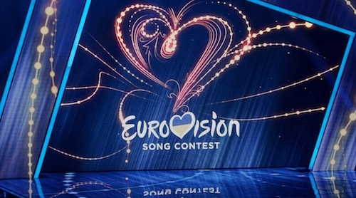promo shot of the Eurovision logo against a blue stage background with a fireworks-style heart and flourishes
