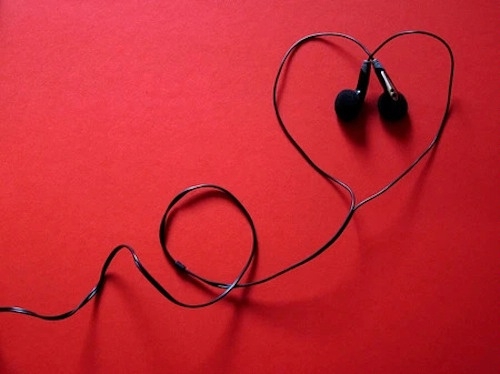 photo of black earphones arranged in the shape of a heart against a red background