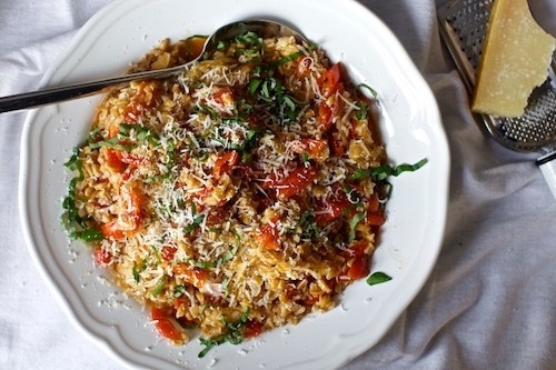 Photo via Smitten Kitchen: a white plate with cooked farro mixed with tomato and basil and topped with shredded cheese