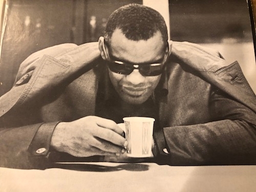 black and white old photo of Ray Charles with paper coffee cup