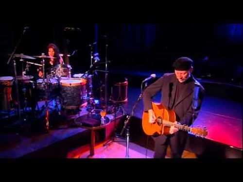 Screenshot from video of Richard Thompson performing on stage with acoustic guitar