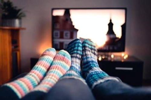Couple with socks and woolen stockings watching movie on tv