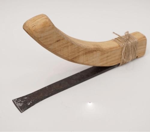 photo of a reproduction ancient adze with metal blade, wooden handle and jute twine