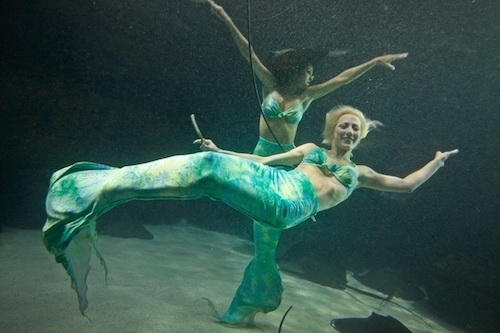 retro color photo of two women dressed as mermaids swimming underwater