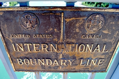 Close-up of weathered sign reading UNITED STATES | CANADA INTERNATIONAL BORDER LINE