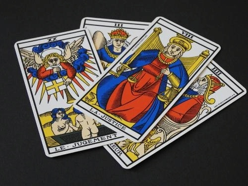 on a black background, four colorful traditional-style tarot cards