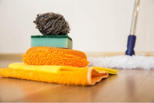 close-up of cleaning items: dust mop, cleaning cloth, sponge, and scrubbers