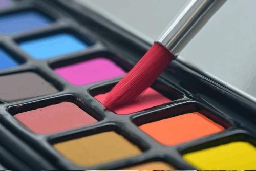 image of a paintbox tray of various vibrant colors and an artist's paintbrush