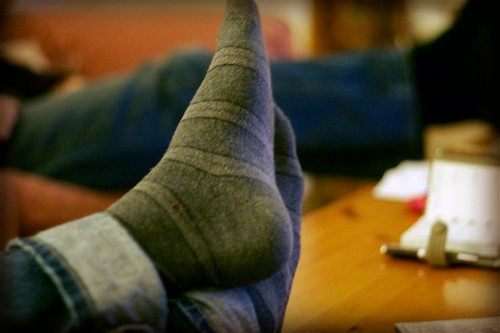 close-up of a pair of feet in gray socks propped up on a coffee table or desk