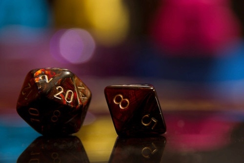 atmospheric photo of 2 multi-sided gaming dice with colorful bokeh lights in background