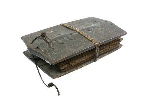 photo of old book with handmade wooden cover with two geckos carved on it bound by string
