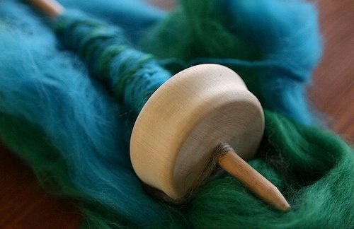 photo of a wooden drop spindle with beautiful blue-green yarn