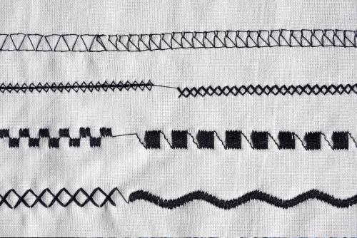 image of sewing machine test stitching in black thread on a white piece of cloth