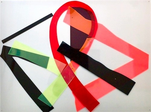 abstract collage of intersecting and looping strips of colorful plexiglas in shades of red, green, yellow, and black, against a white background