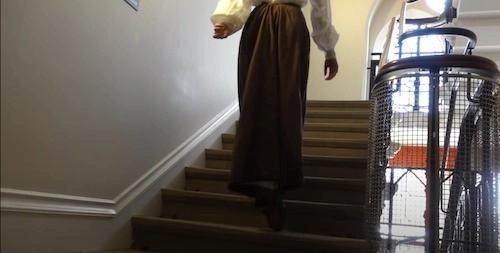 image of woman in long skirt walking up stairs