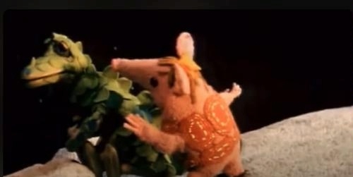 video screenshot of one of the Clangers cute pink, woolen, knitted mouse-like animated aliens attempting to comfort the Soup Dragon