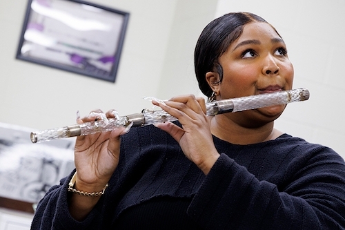 photo of Lizzo playing crystal flute in a casual setting with staff at Library of Congress