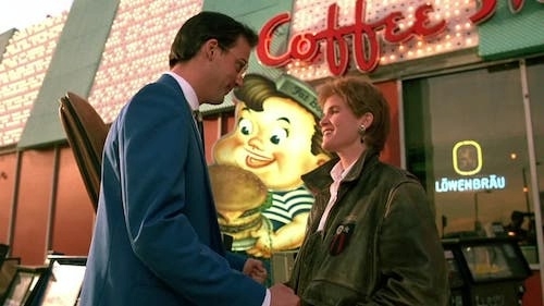 Two characters in conversation outside a retro diner with a bright neon 'Coffee Shop' sign and a large burger advertisement in the background, captured in a vibrant urban setting.