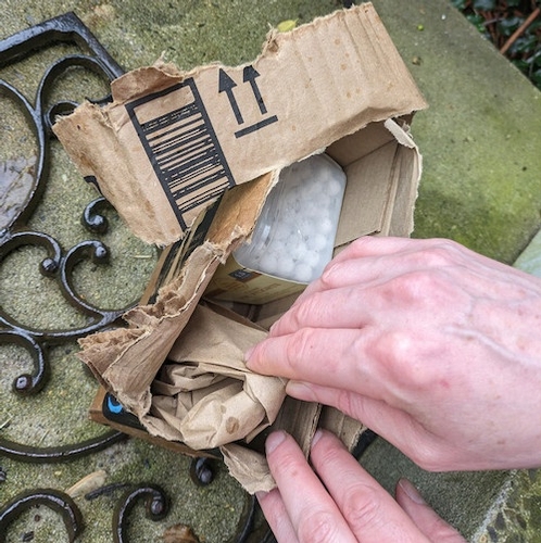 A man's hands opening a smallish Amazon box outdoors