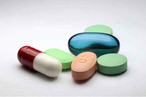 photo of a small number of various pills and capsules on a white background